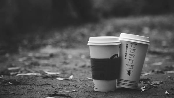 Two single-use Starbucks coffee cups discarded on the ground