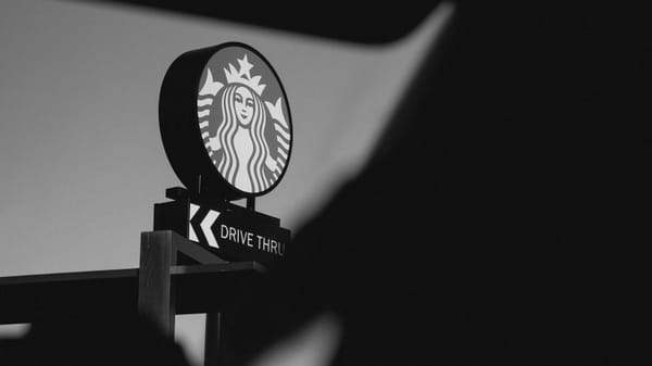 Close up of a Starbucks logo atop a drive-thru sign, taken through a car window