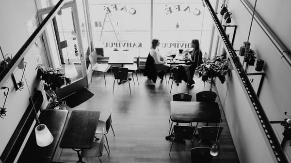 Two people sit chatting over coffee in an otherwise empty cafe